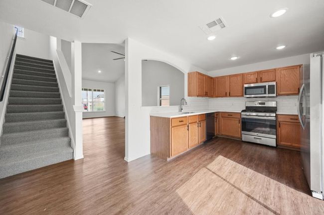 Kitchen featuring a sink, dark wood-style flooring, visible vents, and stainless steel appliances | Image 6
