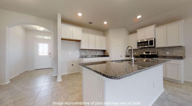 Kitchen with appliances with stainless steel finishes, a sink, decorative backsplash, arched walkways, and an island with sink | Image 4