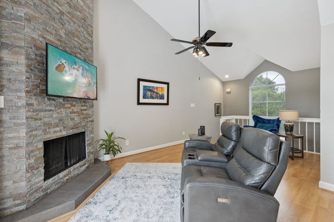Living room with wood finished floors, vaulted ceiling, a ceiling fan, and a fireplace | Image 9