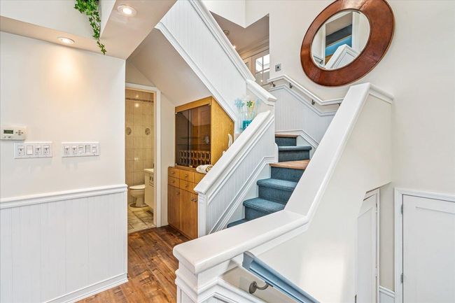 Staircase featuring wood finished floors, a wainscoted wall, and recessed lighting | Image 15