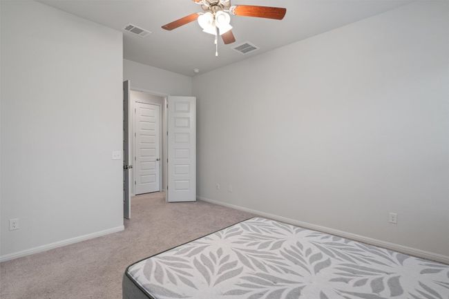 Bedroom with a ceiling fan, light carpet, baseboards, and visible vents | Image 16