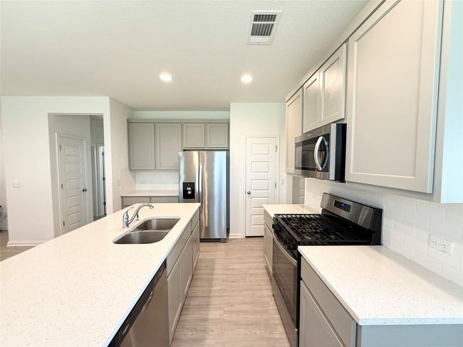Kitchen with stainless steel appliances, a sink, light wood-style floors, gray cabinetry, and tasteful backsplash | Image 10