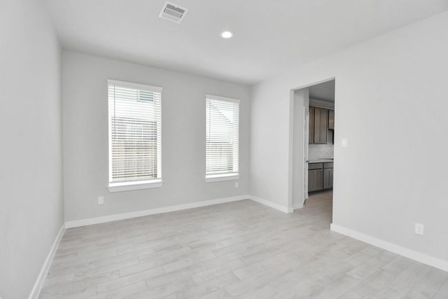 Create lasting memories with your family and friends at the dining table! This expansive dining room showcases sophisticated flooring, custom paint, and seamlessly connects to the family room and kitchen, providing an open and inviting atmosphere. | Image 10