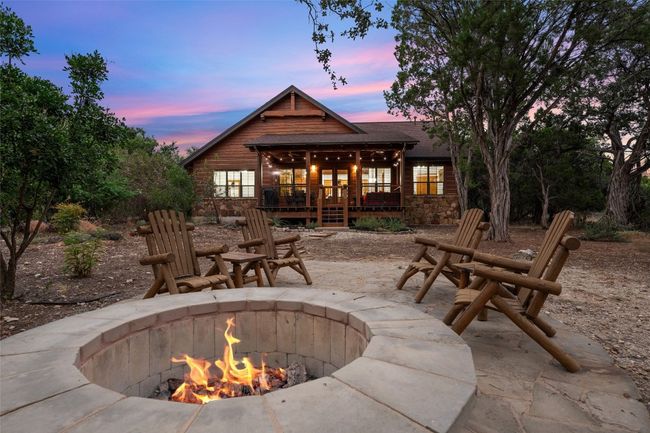 As the sun sets, this cozy fire pit area offers a perfect spot for gathering under the open sky. Adirondack chairs surround the fire, facing the warmly lit back deck, creating an inviting outdoor retreat ideal for evening relaxation and stargazing. | Image 23