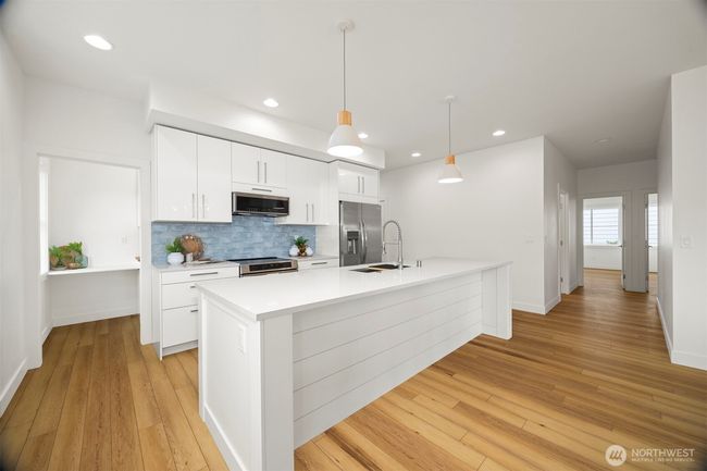 Looking across the island toward the kitchen with the walk-in butler's pantry to the left and the wide hallway to bedrooms and full bathrooms to the right. | Image 10