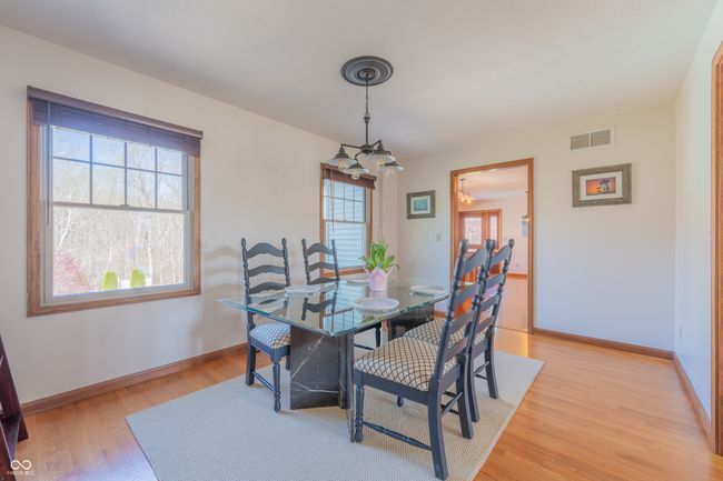 dining space featuring light wood finished floors, baseboards, visible vents, and a chandelier | Image 10