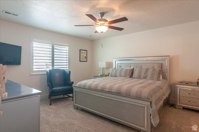 Bedroom featuring light colored carpet, a textured ceiling, and a ceiling fan | Image 16