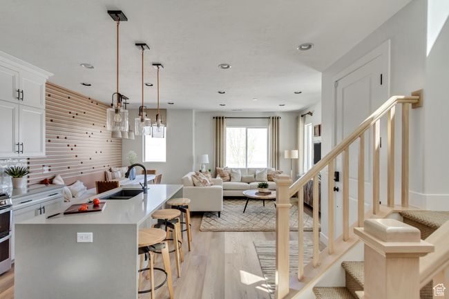 Kitchen featuring a kitchen breakfast bar, light wood-style flooring, open floor plan, recessed lighting, and an island with sink | Image 37