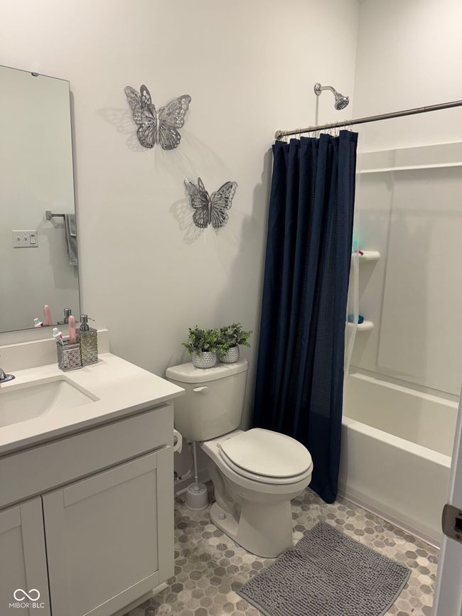 full bath featuring tile patterned flooring, shower / tub combo, toilet, and vanity | Image 7