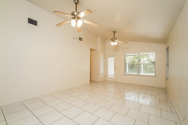 Empty room with vaulted ceiling, a ceiling fan, and light tile patterned flooring | Image 6