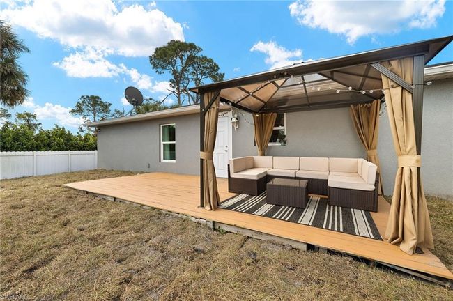 Wooden deck with an outdoor hangout area, a gazebo, and fence | Image 23