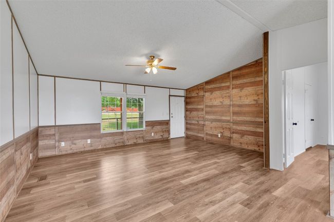 Spare room with lofted ceiling, wood walls, ceiling fan, wood finished floors, and a textured ceiling | Image 9
