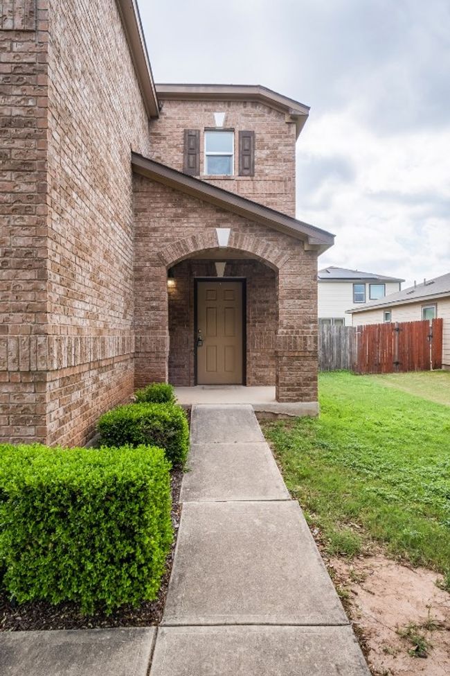 Sidewalk to property featuring a lawn, brick siding, and fence | Image 6