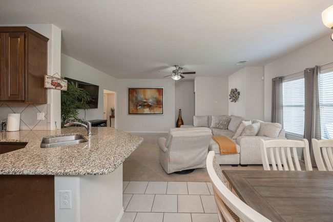Living area with ceiling fan, light tile patterned floors, and light colored carpet | Image 16