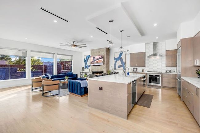 Kitchen featuring a kitchen island with sink, wall chimney range hood, sink, decorative light fixtures, and stainless steel appliances | Image 20