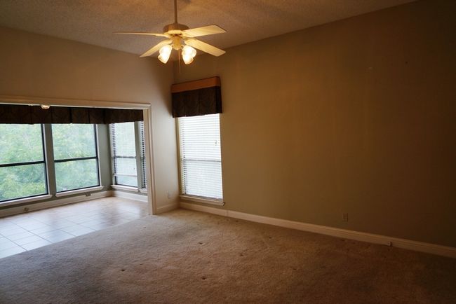 Tiled empty room featuring carpet flooring, a ceiling fan, baseboards, and a textured ceiling | Image 14