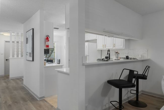 Bar featuring a sink, a textured ceiling, decorative backsplash, light wood-style flooring, and freestanding refrigerator | Image 13