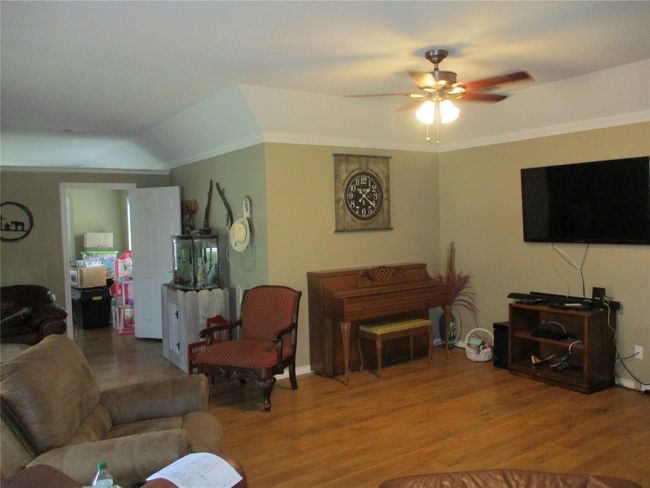 Living room with wood-type flooring, vaulted ceiling, ornamental molding, and ceiling fan | Image 20
