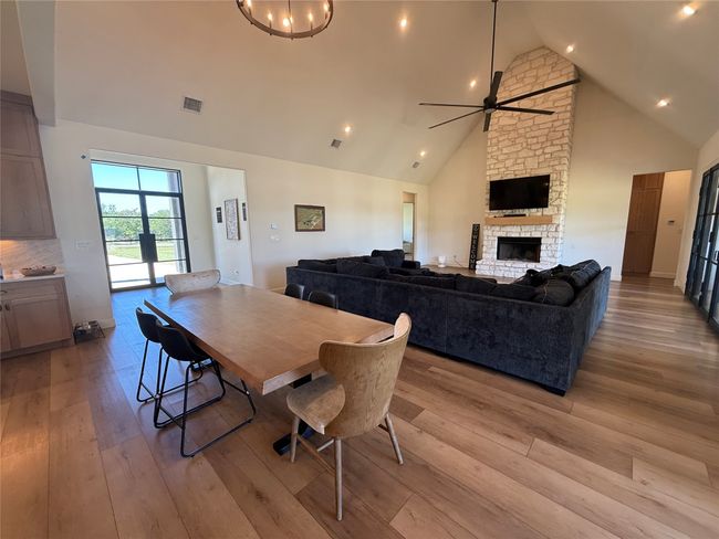 Dining area featuring a ceiling fan, high vaulted ceiling, light wood-style floors, a fireplace, and recessed lighting | Image 27