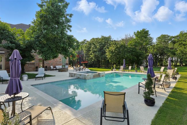 View of swimming pool with hot tub, a patio and wooded yard | Image 30