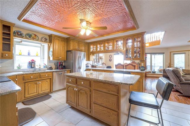 Kitchen featuring appliances with stainless steel finishes, light tile patterned flooring, glass insert cabinets, and open floor plan | Image 15