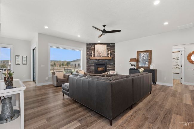 Living room with a ceiling fan, recessed lighting, wood finished floors, and a stone fireplace | Image 10