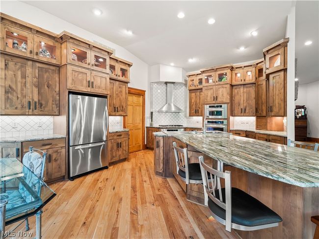 Kitchen with tasteful backsplash, wall chimney exhaust hood, light hardwood / wood-style flooring, and stainless steel appliances | Image 20