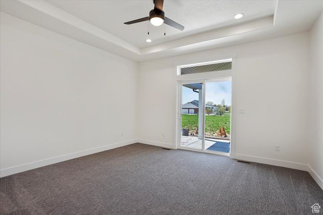 Unfurnished room featuring dark colored carpet, baseboards, a raised ceiling, and a ceiling fan | Image 10