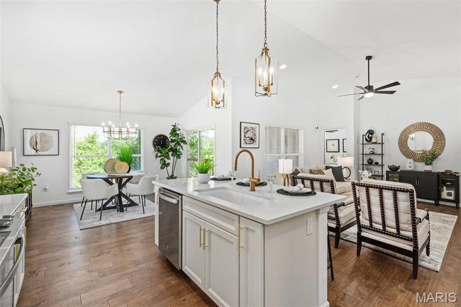Kitchen featuring a chandelier, a sink, stainless steel dishwasher, ceiling fan, and light countertops | Image 15