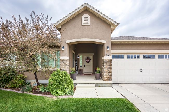 Property entrance featuring stucco siding, stone siding, a garage, and concrete driveway | Image 48