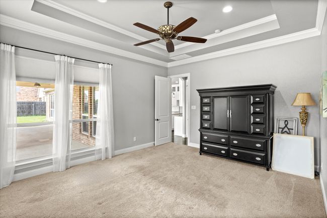 Bedroom with a tray ceiling, carpet flooring, ornamental molding, ceiling fan, and baseboards | Image 17