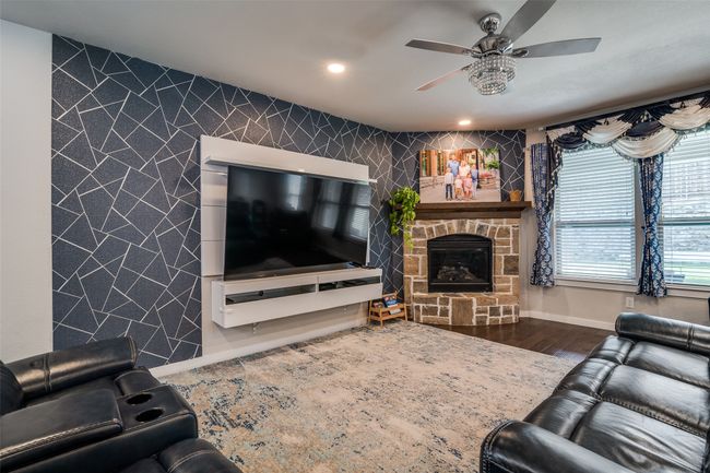 Living area with ceiling fan, an accent wall, a fireplace, recessed lighting, and wood finished floors | Image 8