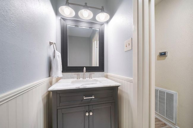 The updated half bath features a marble-topped vanity, brushed nickel fixtures, and modern lighting. | Image 18