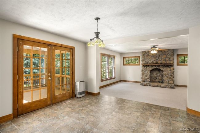 Unfurnished living room featuring ceiling fan, a fireplace, a textured ceiling, and french doors | Image 35