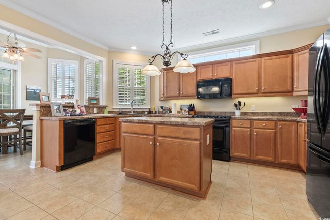 Kitchen featuring visible vents, black appliances, brown cabinets, and a sink | Image 8