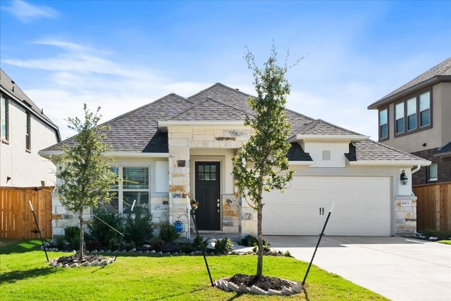 View of front facade with a front lawn, stone siding, fence, concrete driveway, and a shingled roof | Image 35