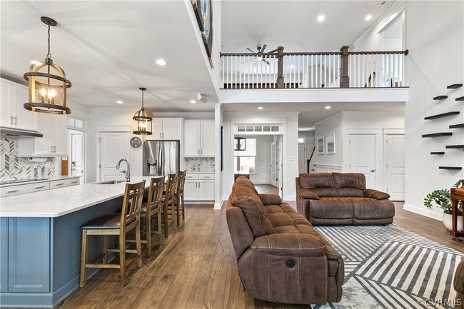 Living room featuring dark hardwood / wood-style flooring, sink, a notable chandelier, and a high ceiling | Image 11