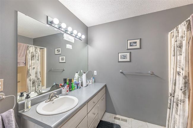Full bathroom featuring tile patterned floors, vanity, a textured ceiling, and a shower with curtain | Image 20