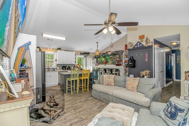 Living area featuring lofted ceiling, a ceiling fan, and light wood finished floors | Image 6