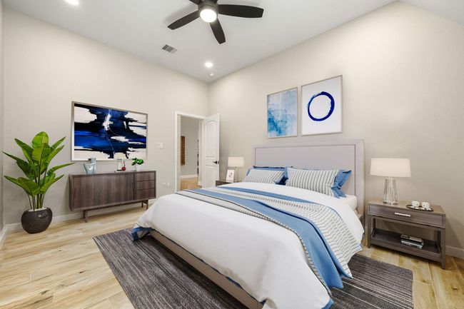 Secondary bedroom features wood like tile flooring, neutral paint, dark stained ceiling fan with lighting and a large window with privacy blinds. | Image 26