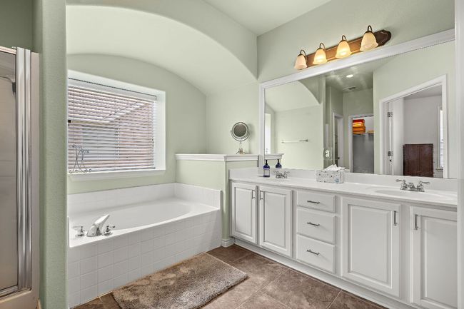 Bathroom with a bath, double vanity, tile patterned flooring, and a shower with shower door | Image 18