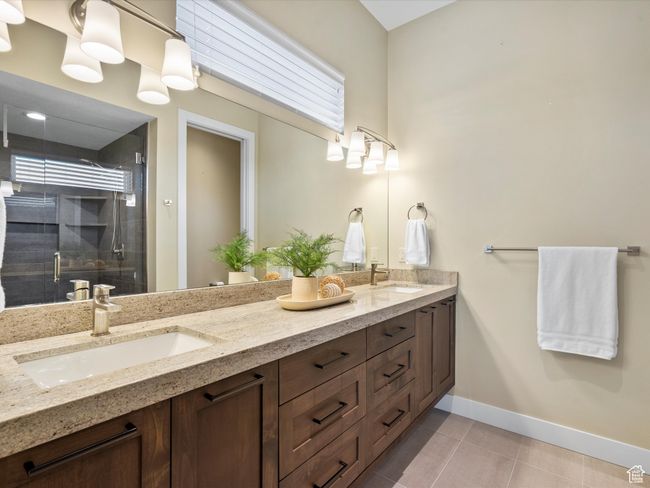 Bathroom featuring double vanity, baseboards, a stall shower, and tile patterned floors | Image 21