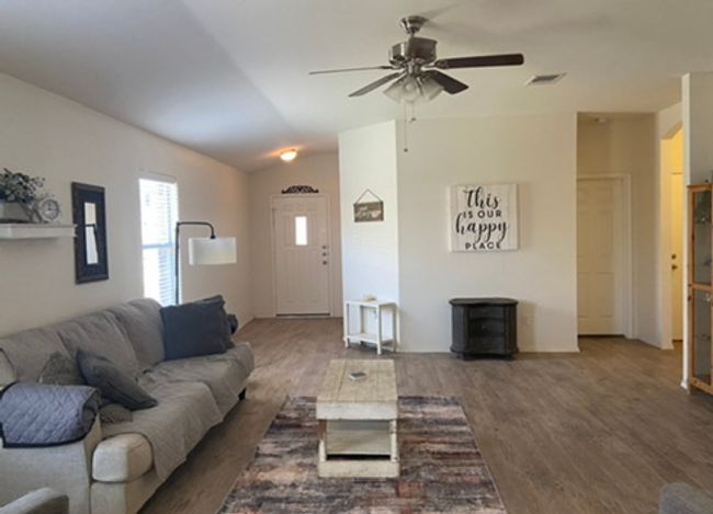 Living area featuring ceiling fan, wood finished floors, vaulted ceiling, and a wood stove | Image 4