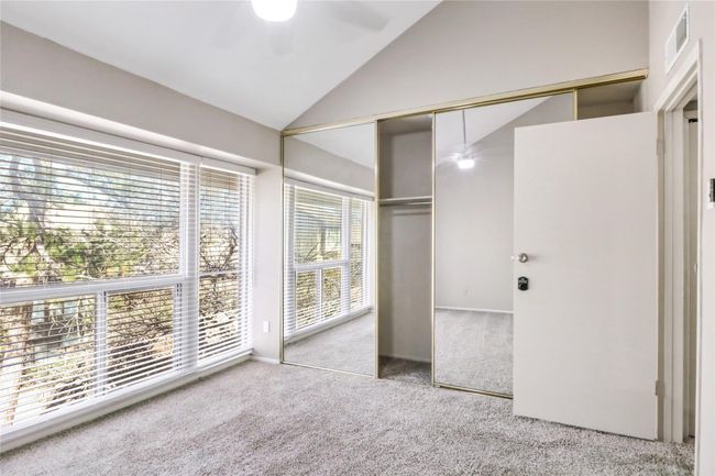 Unfurnished bedroom with carpet floors, high vaulted ceiling, a closet, and a ceiling fan | Image 16