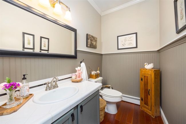 Bathroom featuring a baseboard heating unit, crown molding, toilet, wood finished floors, and vanity | Image 13