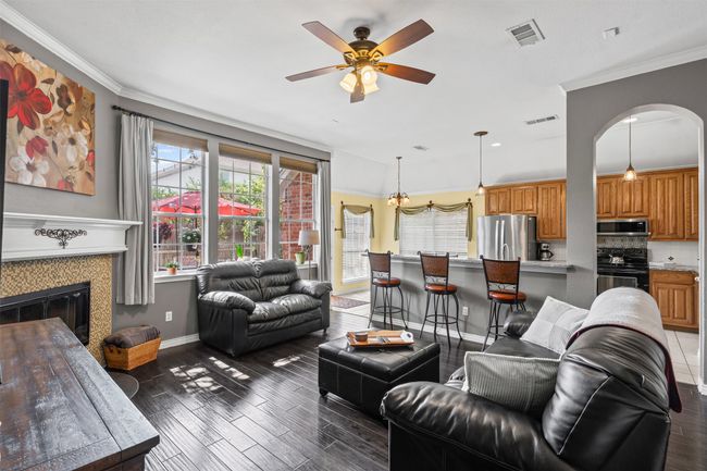 Living area featuring crown molding, ceiling fan, baseboards, plenty of natural light, and wood finished floors | Image 6