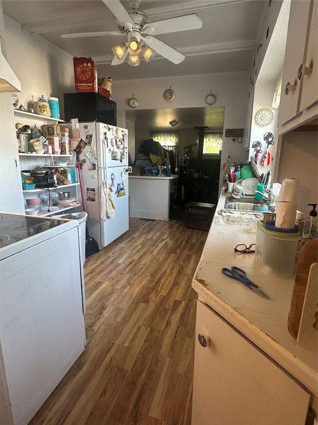Kitchen with range, dark wood-type flooring, exhaust hood, ceiling fan, and refrigerator | Image 11