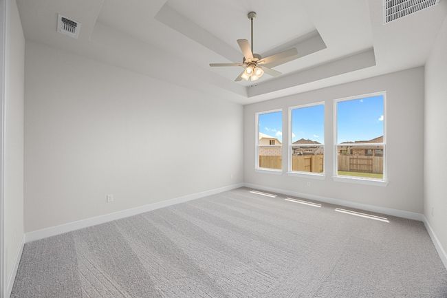 Carpeted empty room with a tray ceiling, baseboards, and a ceiling fan | Image 14