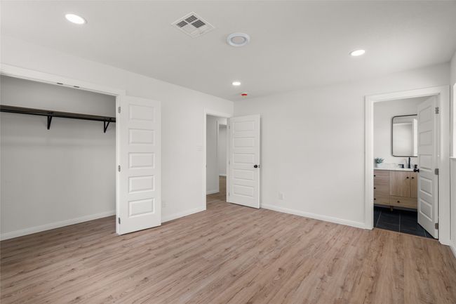 Unfurnished bedroom featuring light wood-type flooring, recessed lighting, baseboards, connected bathroom, and a closet | Image 14