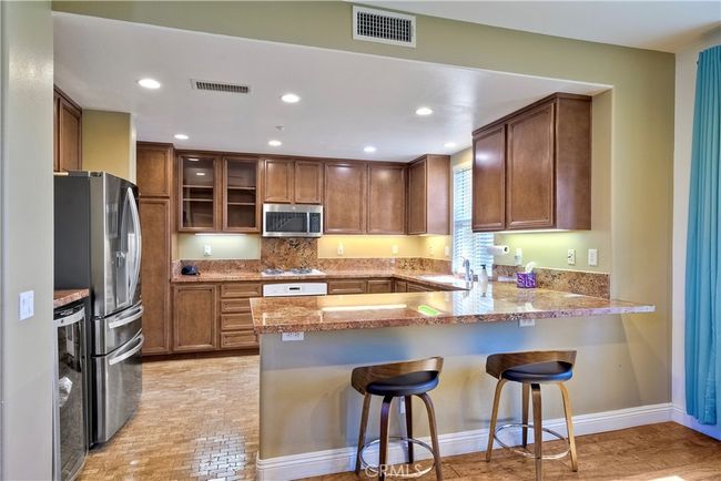 Kitchen offers all the chef would desire, an abundance of storage & cabinetry, glass front cabinets, recessed lighting and wine frig plus large breakfast bar | Image 5